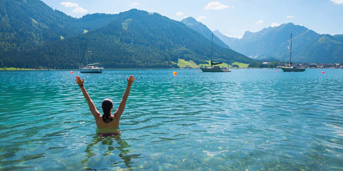 Frau beim Baden am Achensee streckt die Arme aus dem Wasser